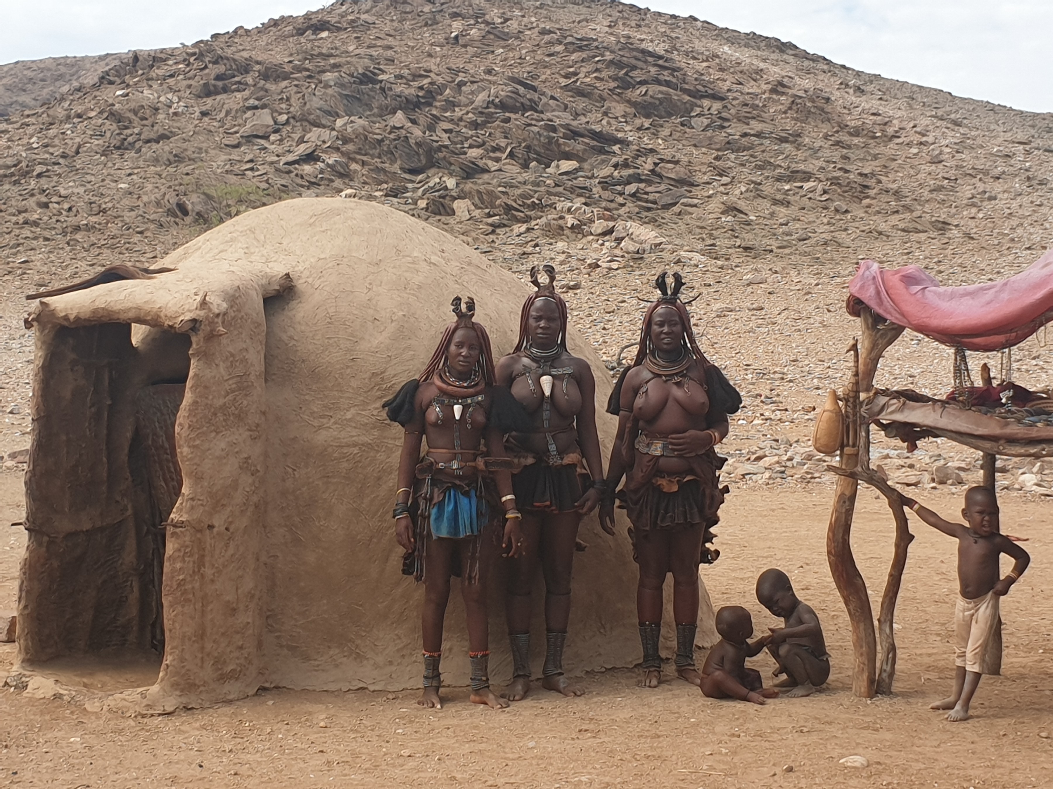 Femmes Himba en habit traditionnel devant une case, Désert du Namib, Namibie. 